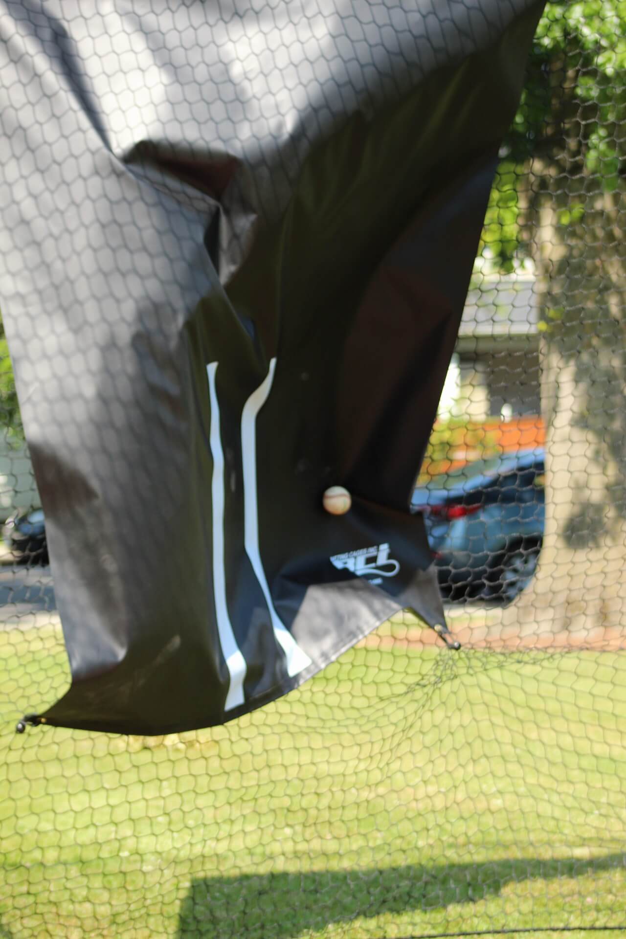 Vinyl backdrop getting hit by baseballs while inside the trapezoid batting cage