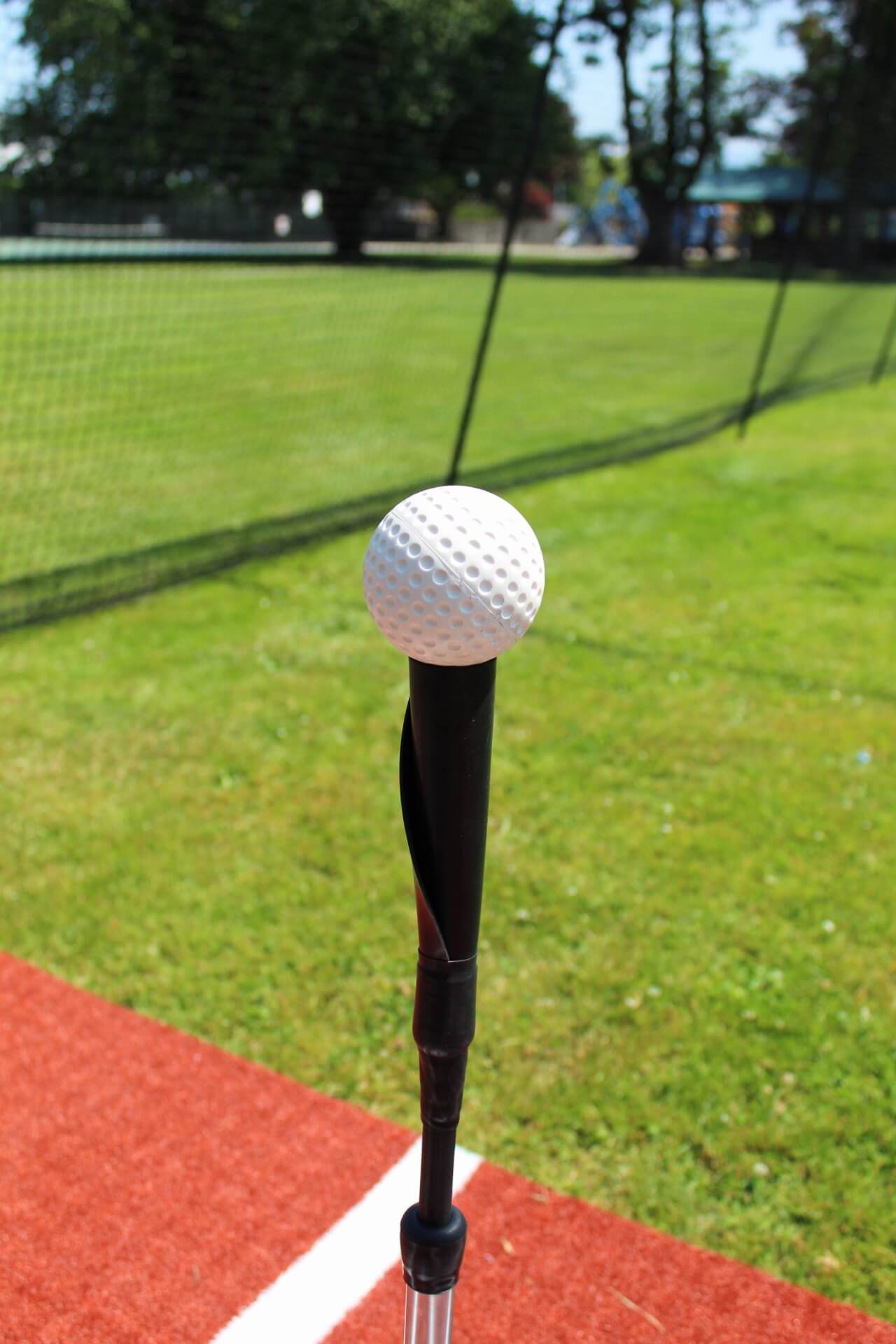 White dimpled baseball ontop of tanner tee in batting cage