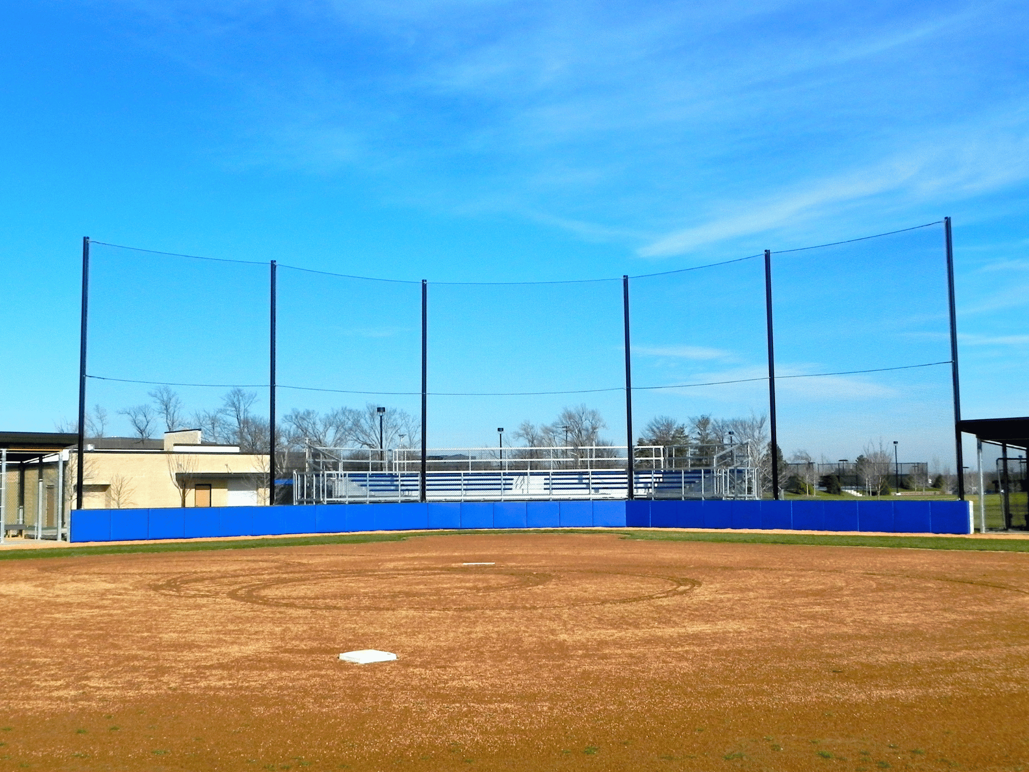 Backstop Netting with Blue Padding on a baseball field looking at homeplate