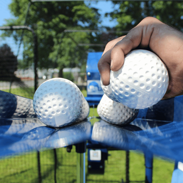 Man loading Bata auto feeder with white dimpled baseballs
