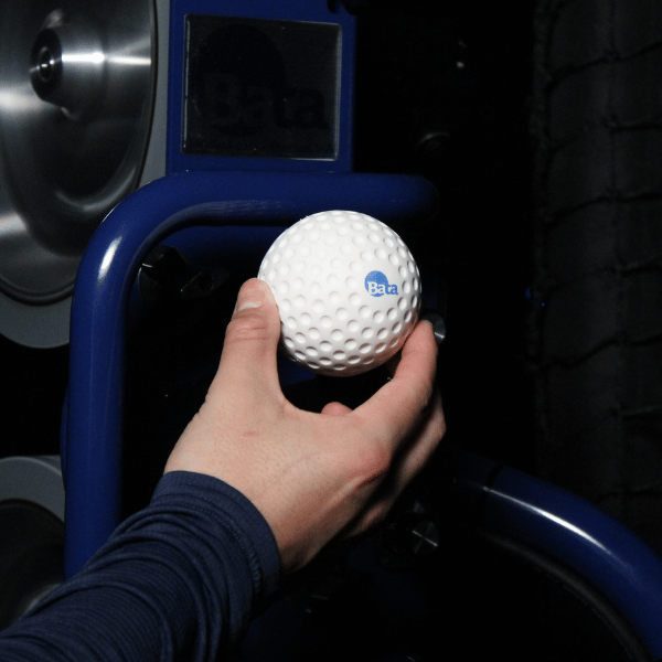 Man putting the lightweight bata dimpled baseball in to the bata 2 pitching machine