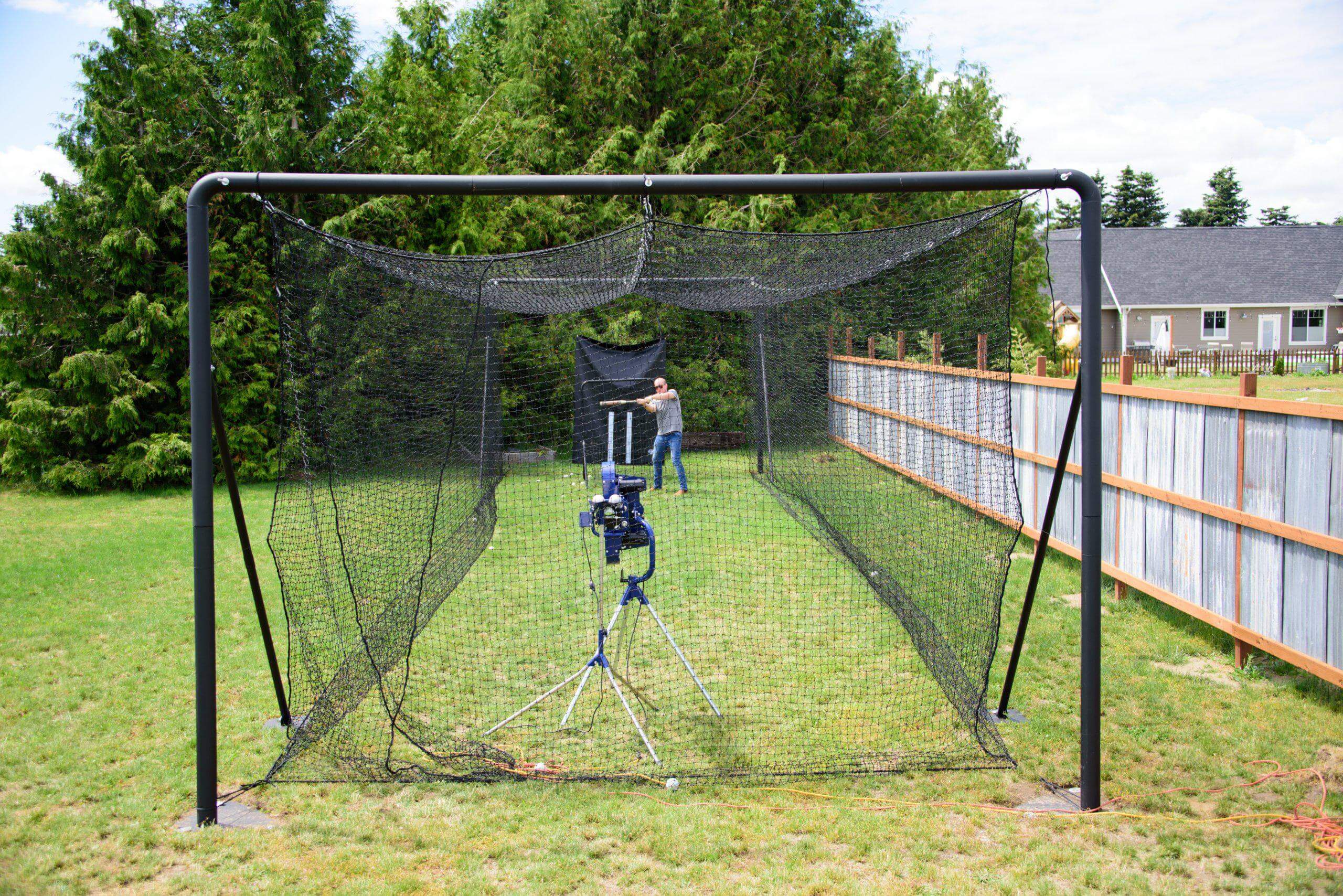 Front view of the Iron Horse batting cage with man batting