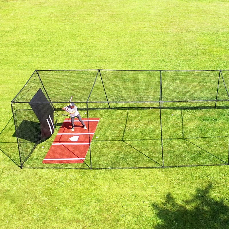 Man batting in the Freestanding Trapezoid Batting Cage with the clay batters box and vinyl backdrop behind him