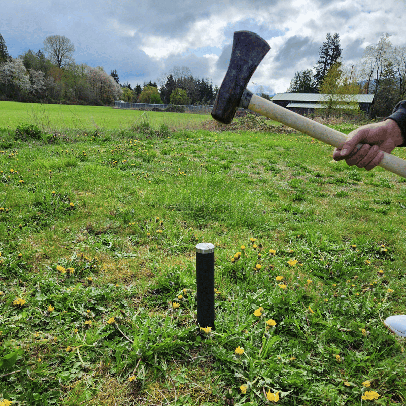 Man hammering concrete free ground sleeves in the ground