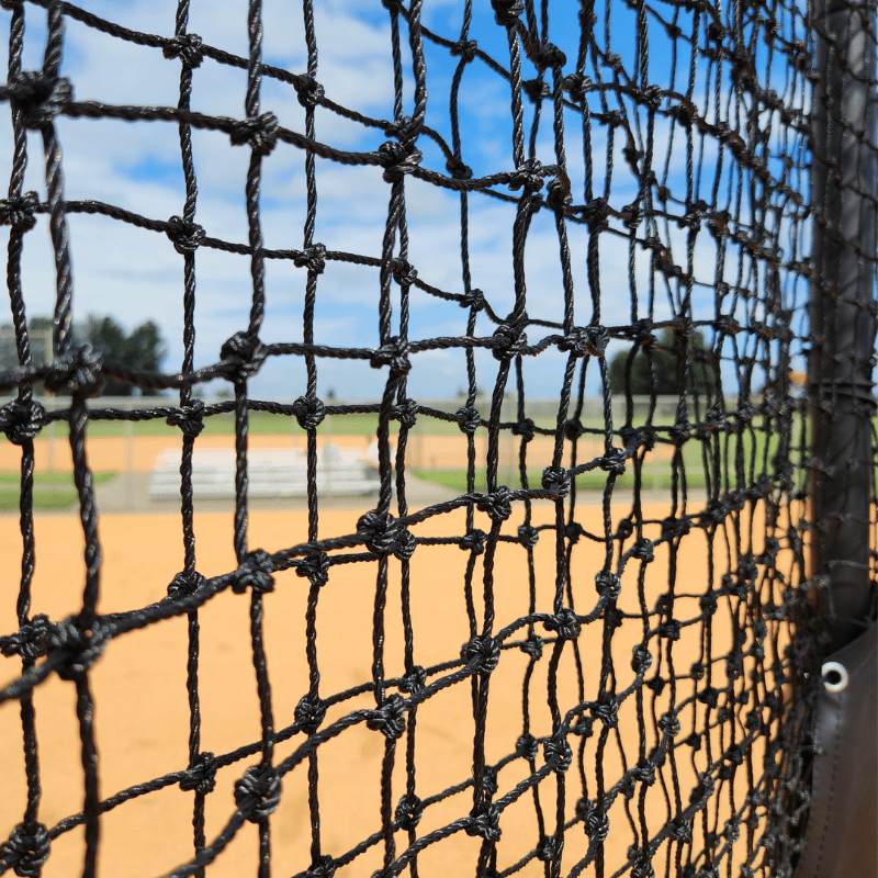 A baseball field featuring the BATTING CAGES INC Armadillo Protective L-Screen (Aluminum) and a black bucket on the pitcher’s mound under a clear sky.