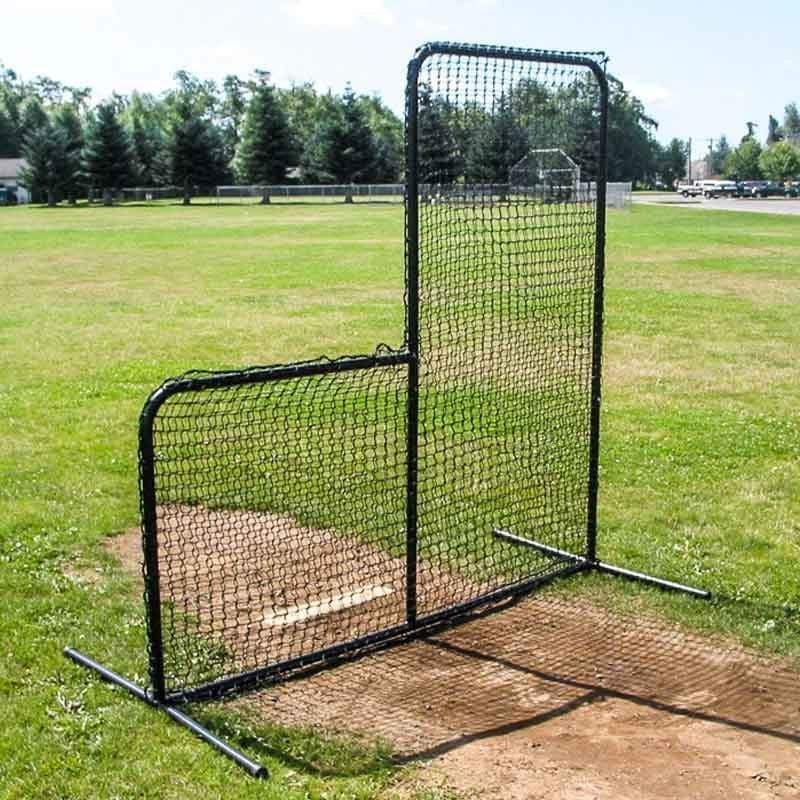 A person practices hitting inside the 10-Foot Wide Batting Cage System by BATTING CAGES INC, set up on a grassy lawn with durable HDPE netting; a small building and clear sky are visible in the background.