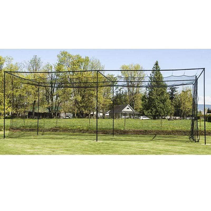 A person practices hitting inside the 10-Foot Wide Batting Cage System by BATTING CAGES INC, set up on a grassy lawn with durable HDPE netting; a small building and clear sky are visible in the background.