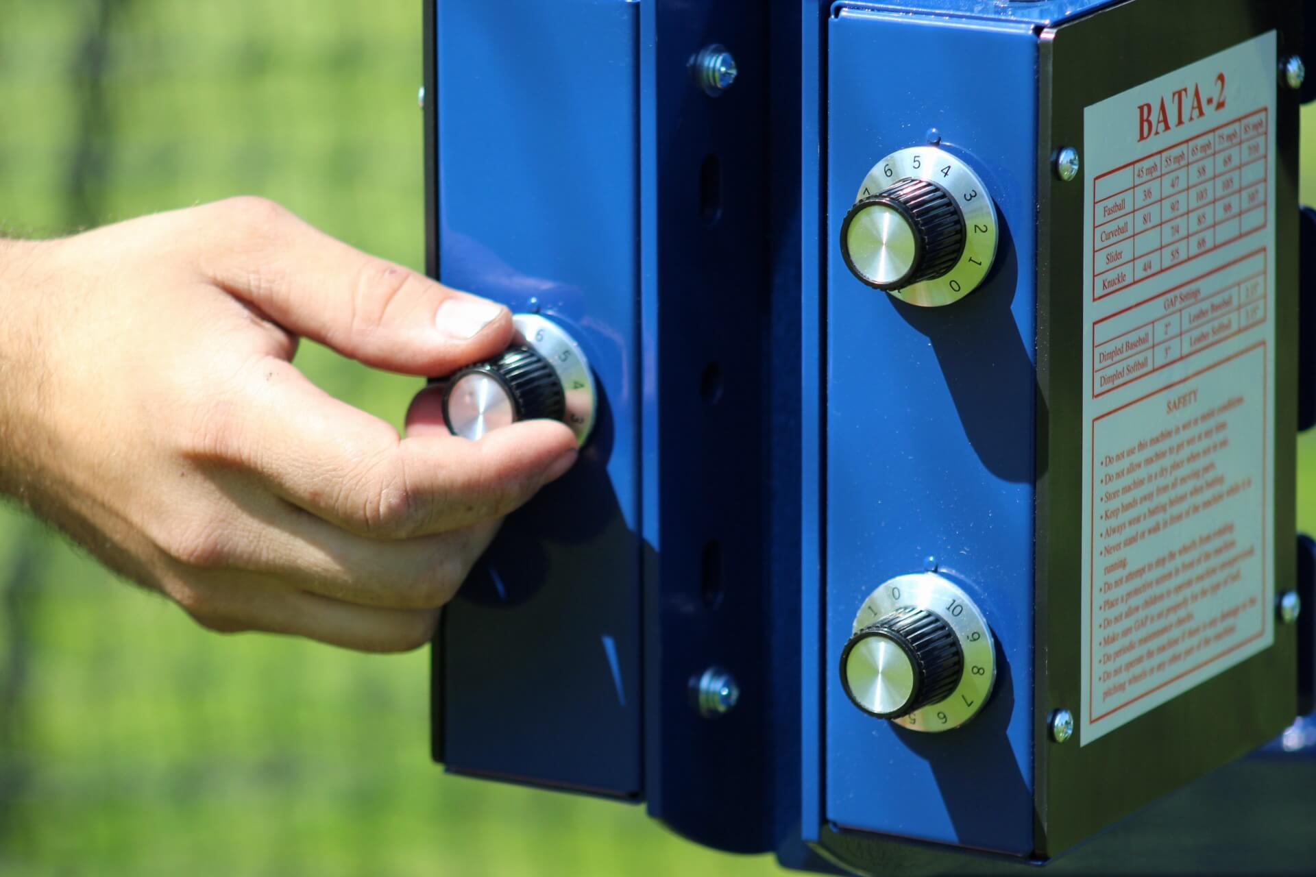 Man changing the speed of the Bata 2 pitch 3 pitching machine