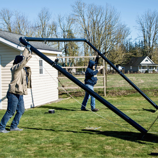 2 men standing up the Iron Horse batting cage frame