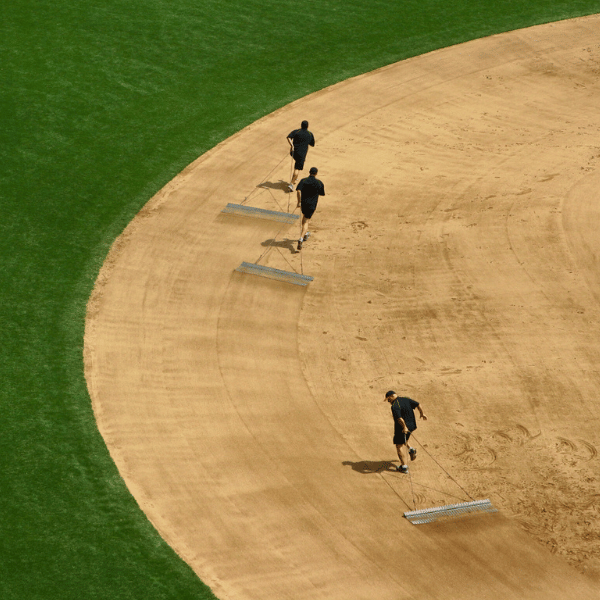 Three men dragging drag mats along the baseball infield