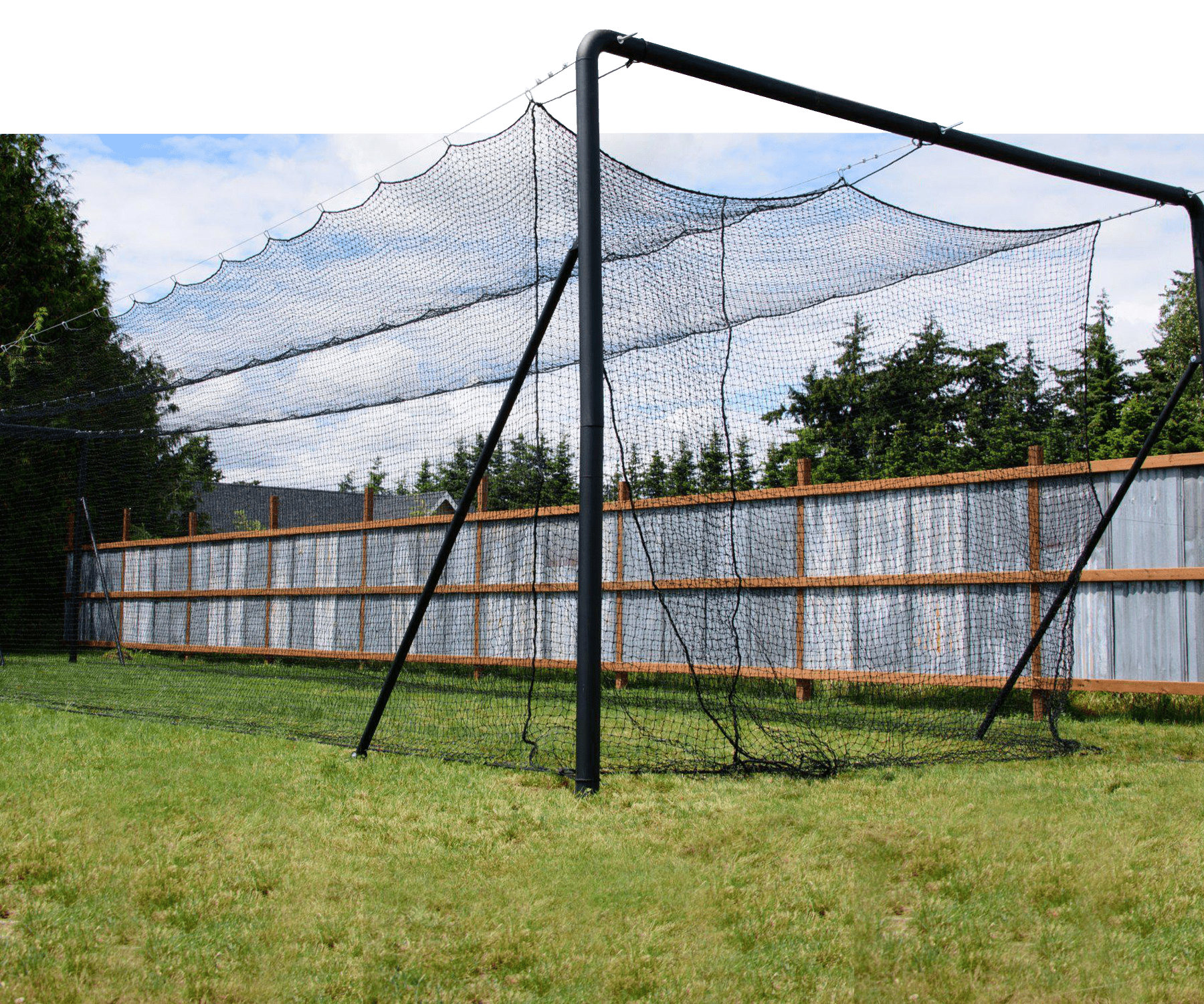 Iron Horse batting cage in backyard with fence, grass, trees, and blue skies