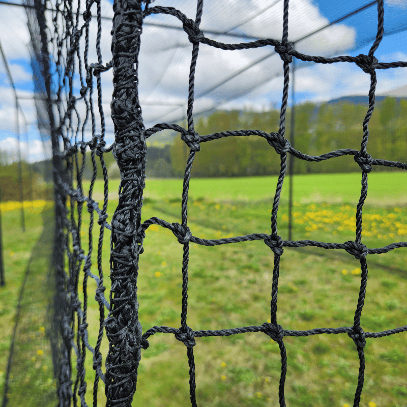 #42 Square Hung Knotted KVX200™ close up of the netting meshes with green grass and blue cloudy skys